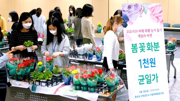 <사진설명> 3일 광화문 우리카드 본사에서 진행된 ‘화훼농가 돕기 게릴라 마켓 행사에서 우리카드 임직원들이 꽃 화분을 구매하고 있다.