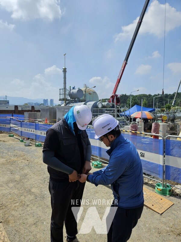 김환용 가스공사 안전기술부사장이 현장 근로자에게 아이스 조끼를 입혀주고 있다.