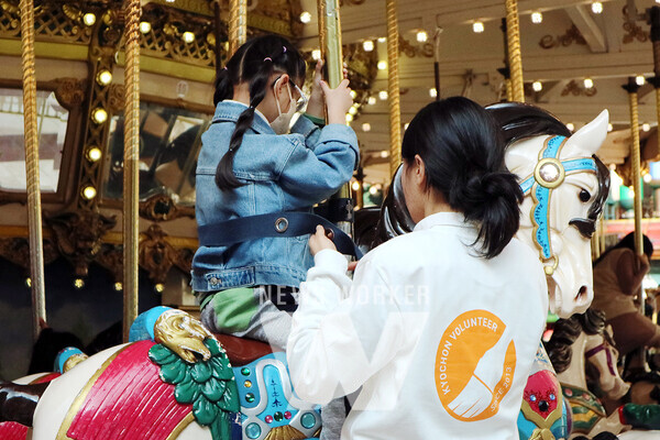 지난 13일(수) 교촌에프앤비 바르고 봉사단원이 시각장애 아동이 안전하게 놀이기구를 즐길 수 있도록 지원하고 있는 모습