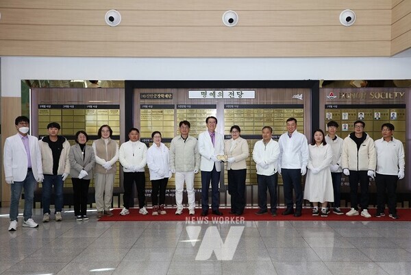 신안군정원수사회적협동조합 장산면 작목반 회원들과 기탁식 참석자들이 신안군청 명예의 전당에서 현판을 게시하며 기념 촬영을 하고 있다