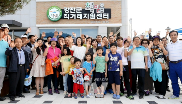관광객들이 강진군 직영 초록믿음 직거래지원센터 앞에서 손을 흔들며 즐거워하고 있다.