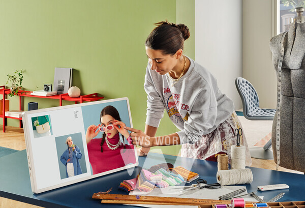 모델이 LG 스탠바이미 2의 화면부를 분리해 테이블 위에 세워두고 터치를 통해 회의 자료를 넘기고 있다.