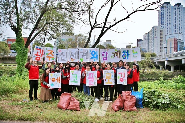 광주신세계 임직원 봉사단이 광주천변에서 에코 플로깅과 유해식물 제거 활동을 펼친 후 기념사진을 찍고 있다